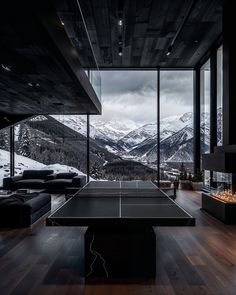 a ping pong table in the middle of a room with large windows overlooking mountains