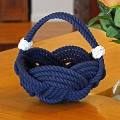 a blue basket sitting on top of a wooden table next to a vase with flowers