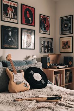 a bedroom with pictures on the wall and a guitar laying on the bed in front of it