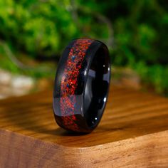 a black ring with red speckles on it sitting on top of a wooden table