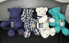 several teddy bears are lined up on a black blanket in a crib, one is blue and the other is white