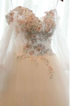 a wedding dress hanging on a hanger in front of a window with sheer curtains