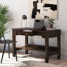 a wooden desk with a laptop on it next to a chair and potted plant