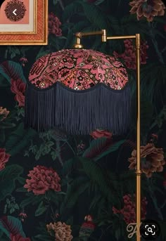 an ornate lamp with tassels on it in front of a floral wallpaper