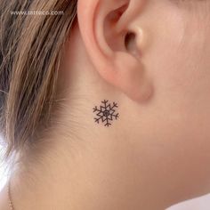 small snowflake tattoo on girl behind ear