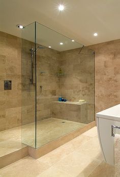 a bathroom with a glass shower door and beige tile walls, along with a white sink