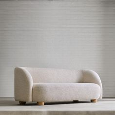 a white couch sitting on top of a cement floor next to a brick wall in an empty room