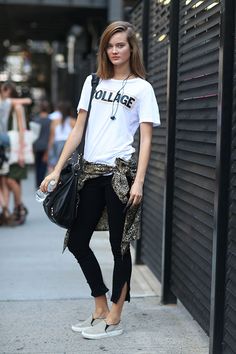 a young woman is standing on the sidewalk