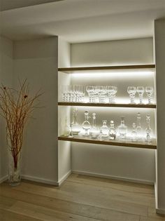 an empty room with several shelves and vases on the wall in front of it