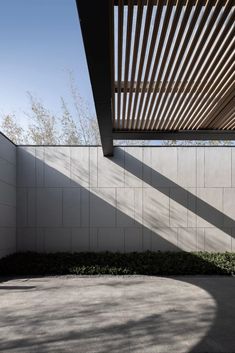 an outdoor area with concrete walls and wooden slats on the ceiling, surrounded by greenery