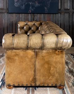 a brown leather couch sitting on top of a rug next to a wooden paneled wall