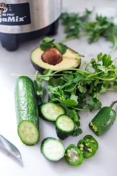 cucumbers, avocados, and parsley on a counter next to an air fryer