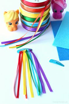 there are many different colored ribbons on the table next to some toy figures and tape