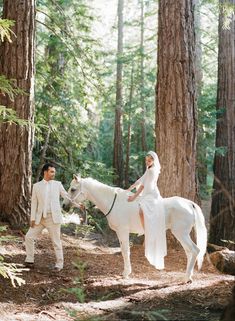 a bride and groom are riding on a horse in the woods