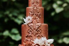 a three tiered cake decorated with flowers and feathers