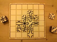 a tile with black and white designs sitting on top of a wooden table next to other tiles