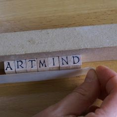 the word artmnd spelled with scrabble blocks in front of a person's hand