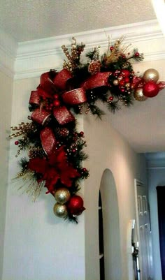 a christmas wreath hanging on the wall with red and gold ornaments around it's edges