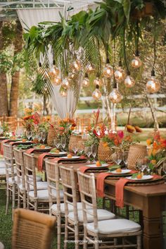 a long table is set up for an outdoor dinner with orange and pink flowers on it