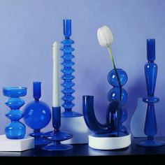 blue vases and candles on a table with a single flower in the middle one