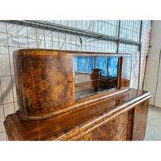 an old wooden dresser sitting in front of a tiled wall with a mirror on it