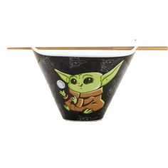 a star wars yoda cup with chopsticks sticking out of the top and an image of baby yoda on it