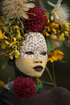 a woman's head is adorned with flowers and leaves in the shape of a face