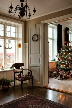 a living room with a christmas tree in the corner and a chair next to it