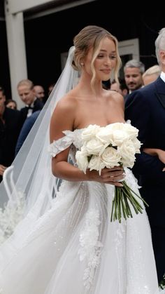 the bride is walking down the aisle with her bouquet in hand as she looks on