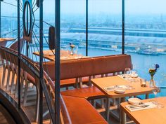 an empty restaurant with tables and chairs overlooking the cityscape in front of large windows