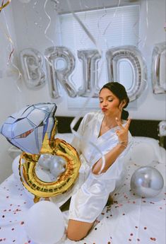 a woman sitting on top of a bed next to balloons