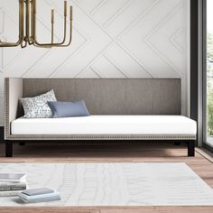 a daybed with pillows, books and a chandelier