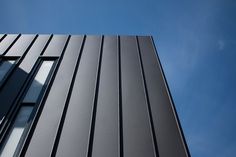 the side of a tall building with lots of windows on it's sides, against a blue sky