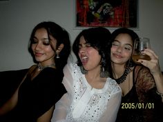 three women sitting next to each other holding wine glasses in their hands and laughing at the camera