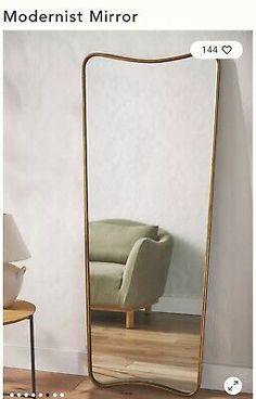 a large mirror sitting on top of a wooden floor next to a chair and table