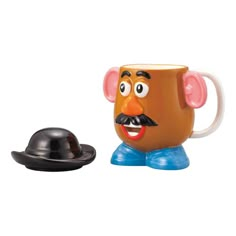 a coffee cup with a hat on it next to a small toy elephant's head