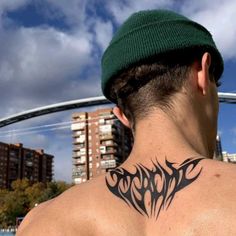 a man with a black tattoo on his back neck and shoulder is standing in front of some tall buildings