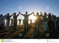 a group of people standing on top of a grass covered hill with their arms in the air