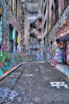 an alley with graffiti all over the walls and on the ground in front of it