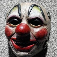 a close up of a clown's face on a carpeted floor with grey walls