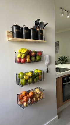 two metal baskets filled with fruit on top of a kitchen wall next to an oven