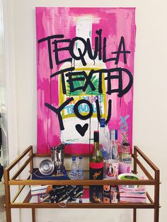 a shelf with bottles and glasses on it in front of a painting that reads tequila next to you