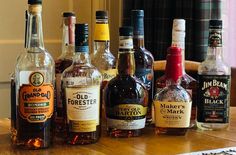 several different types of liquor sitting on top of a wooden table next to each other