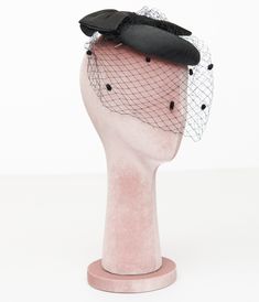 Step back in time with an enchanting accessory that adds a touch of classic elegance to any outfit! This charming 1950s pillbox hat from Unique Vintage, features a delightful oversized black bow perched atop, perfectly complemented by its delicate mesh veil. Whether you're attending a garden party or simply want to elevate your everyday style, this fascinator is sure to turn heads and spark conversations..Available while supplies last. | Unique Vintage 1950S Black Bow Pillbox Fascinator Hat Black Cloche Fascinator For Evening, Black Evening Cloche Fascinator, Adjustable Black Fascinator For Vintage Events, Black Mini Hat With Pinched Crown For Evening, Black Bow Fascinator For Formal Occasions, Black Bow Fascinator For Evening, Black Bow Fascinator For Wedding, Tulle Fascinator For Kentucky Derby Evening, Kentucky Derby Evening Tulle Headpiece