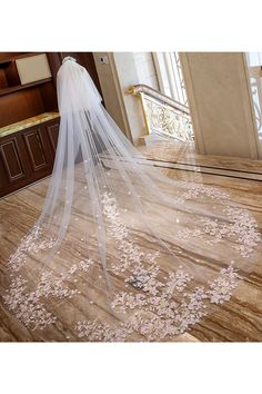 a wedding veil with pink flowers on the bottom is shown in front of a doorway