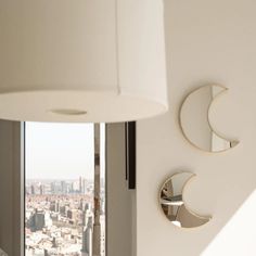 two circular mirrors mounted to the side of a wall next to a lamp and window