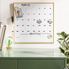 a desk with a calendar on it and a cactus in the corner next to it