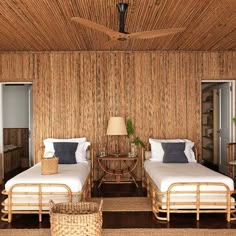 two beds in a room with wooden walls and ceiling fan on top of the headboard