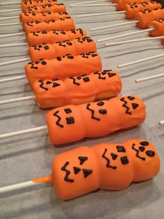 several orange candy sticks with black icing on them are lined up and ready to be eaten