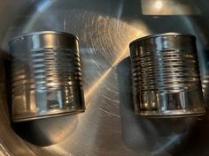 two metal cups sitting on top of a silver object in the middle of a circle